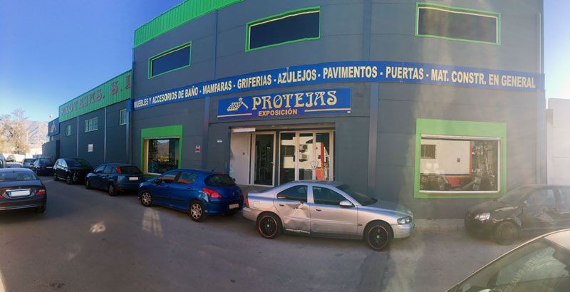 Una fila de coches están aparcados delante de un edificio.