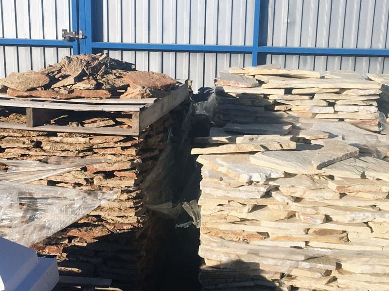 Una pila de madera está delante de una valla azul.