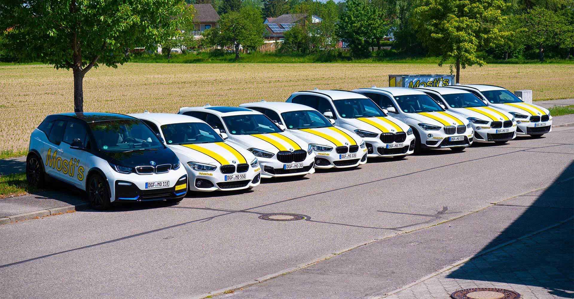 Eine Person hält ein Lenkrad, während eine andere im Inneren eines Autos auf einem Klemmbrett schreibt.