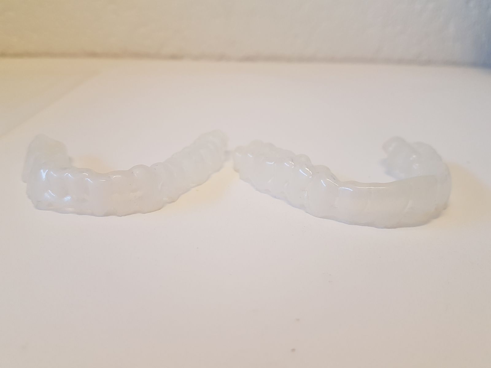 Deux protège-dents transparents sont posés sur une table blanche.