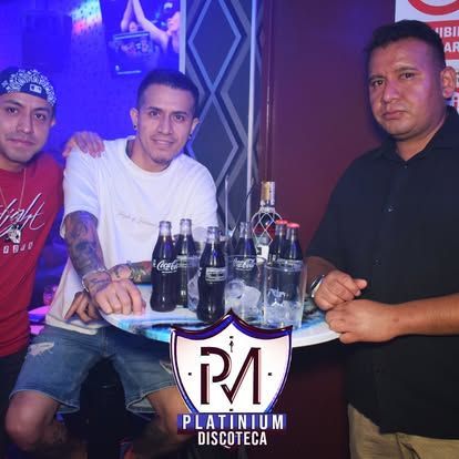 Tres hombres en una discoteca. Uno sostiene una bandeja de bebidas. El logo de Platinum Discoteca está abajo.
