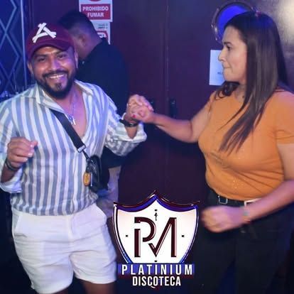 Gente bailando en una discoteca; hombre con camisa de rayas, mujer con top naranja, logo 