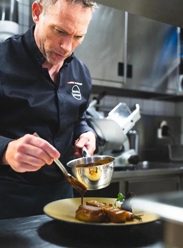 Le chef nappe de jus un plat de viande en cuisine