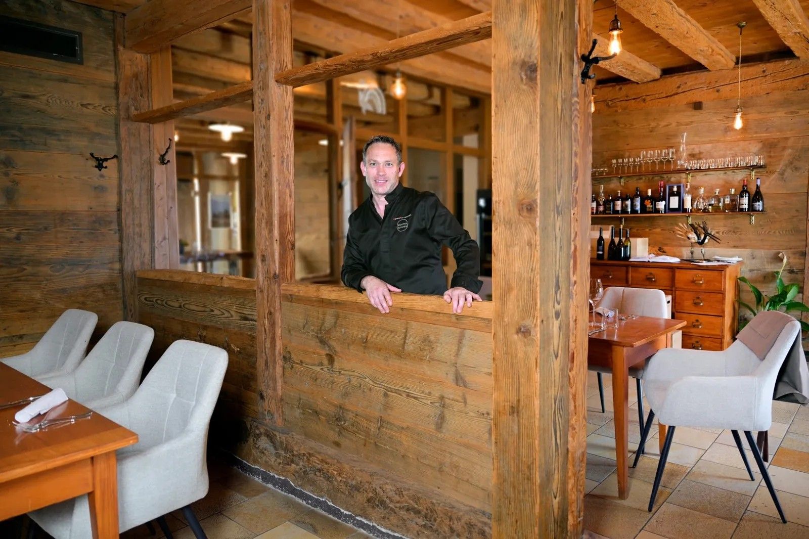 Sébastien Rithner, souriant, accoudé à la cloison de bois de la salle à manger