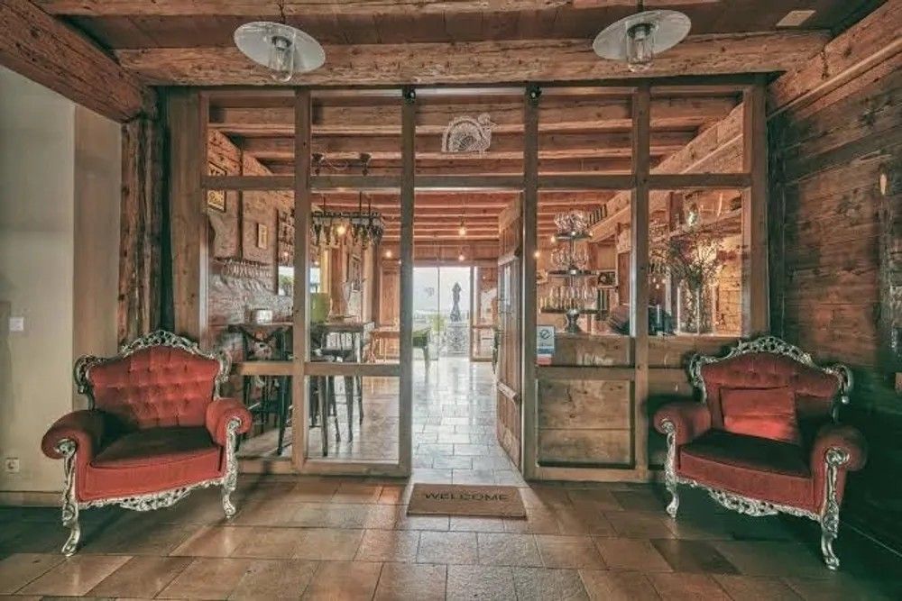 L'entrée du restaurant, deux fauteuils baroques rouges de part et d'autre de la cloison vitrée en bois