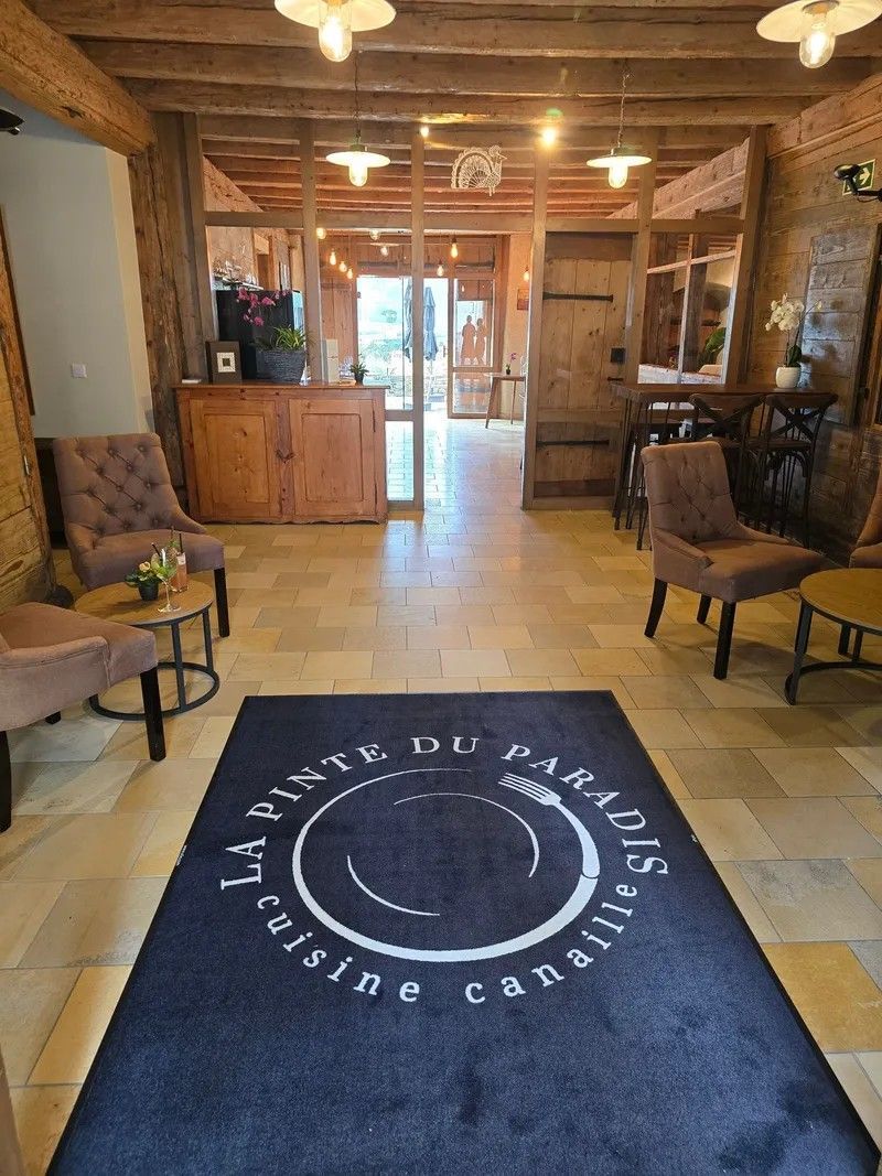 Hall d'entrée du château : boiseries, carrelage de pierre et tapis au logo de la maison