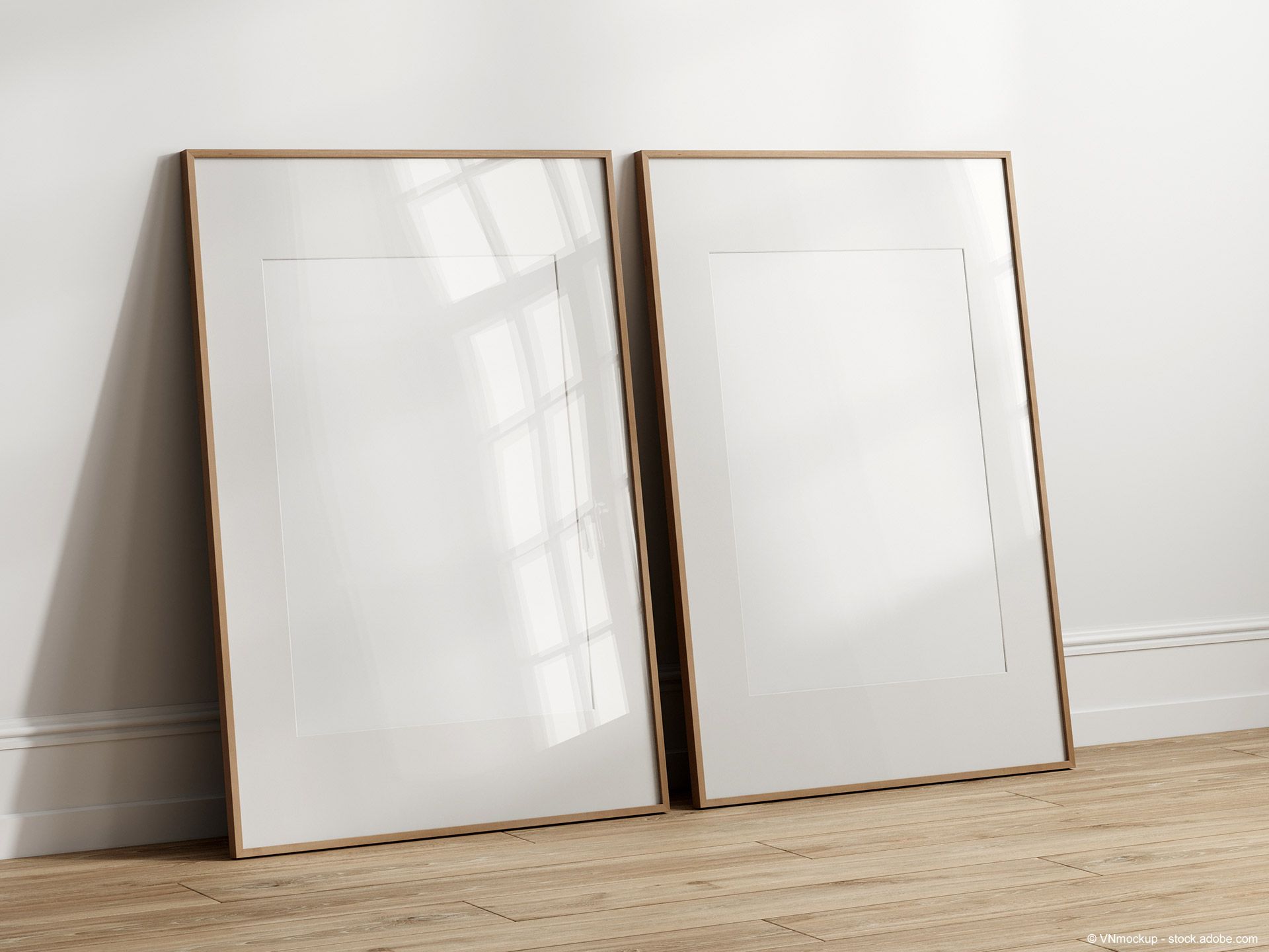 Zwei leere Holzrahmen mit Glaseinsatz lehnen an einer weißen Wand.