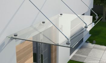 Abgehängtes Glasvordach über Eingangstür, mit stabilen Zugstangen an der Fassade befestigt.