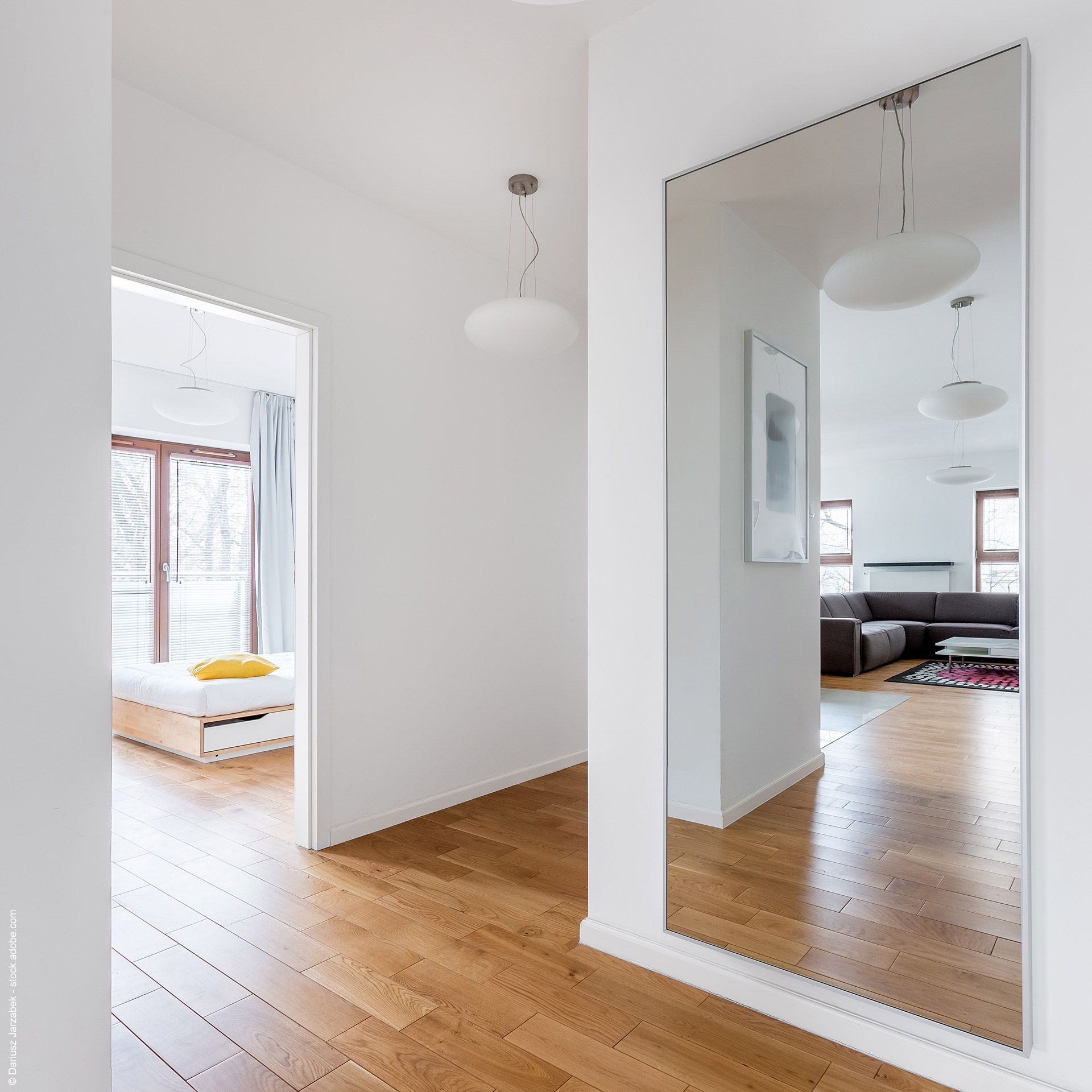 Heller Flur mit Holzboden und großem Wandspiegel für mehr Lichttiefe und Weite.