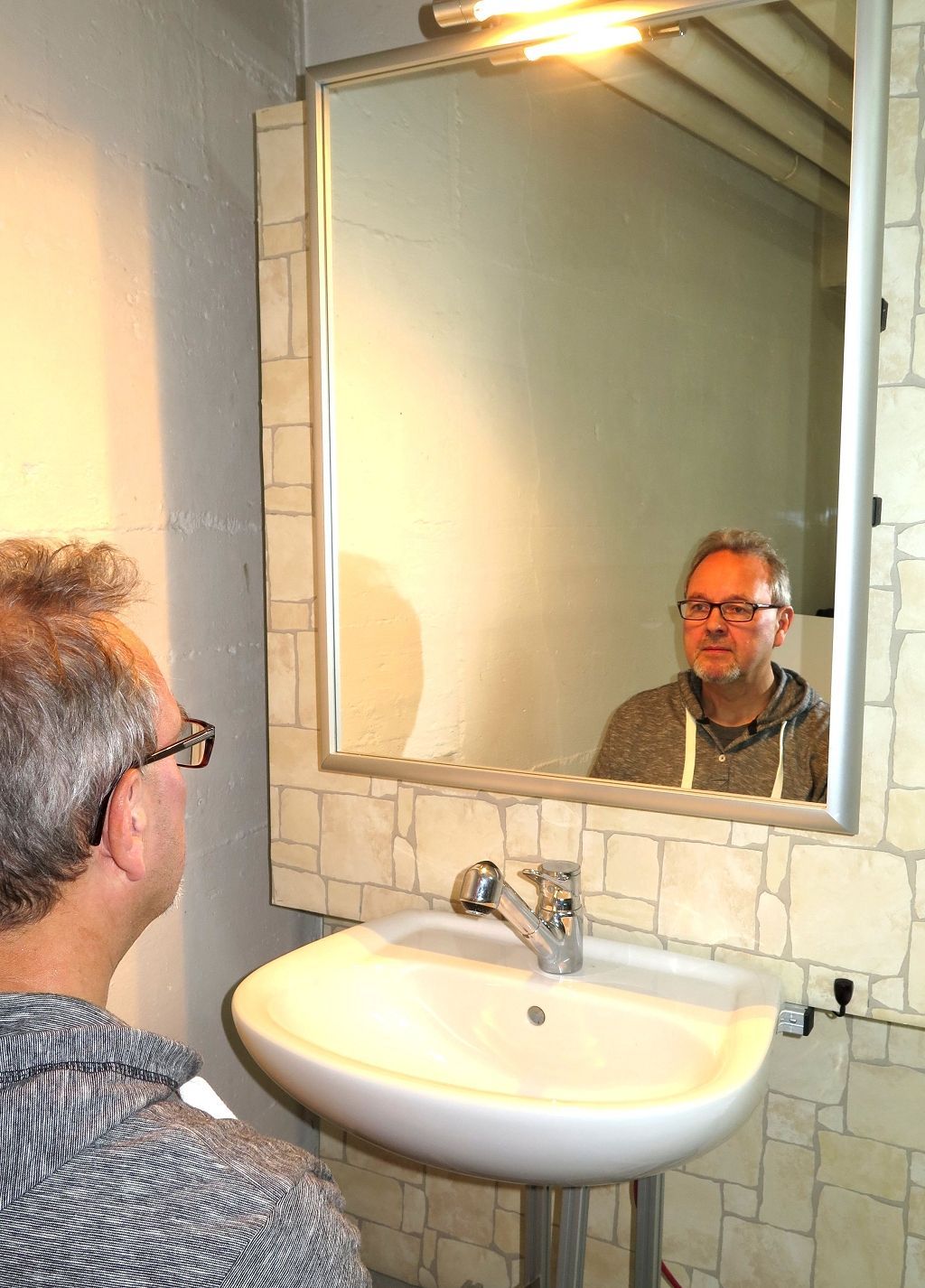 Elektrischer Kippspiegel in aufrechter Position über dem Waschbecken.