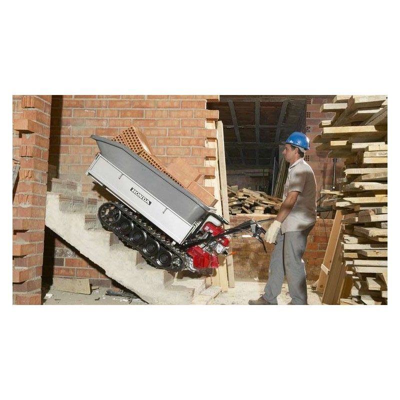 Un ouvrier du bâtiment sur un chantier monte des briques très lourdes à l'aide d'un transporteur HONDA