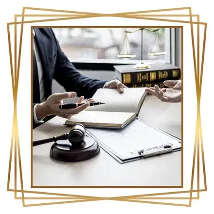 Abogado discutiendo documentos con un cliente, balanza de la justicia, mazo sobre la mesa.