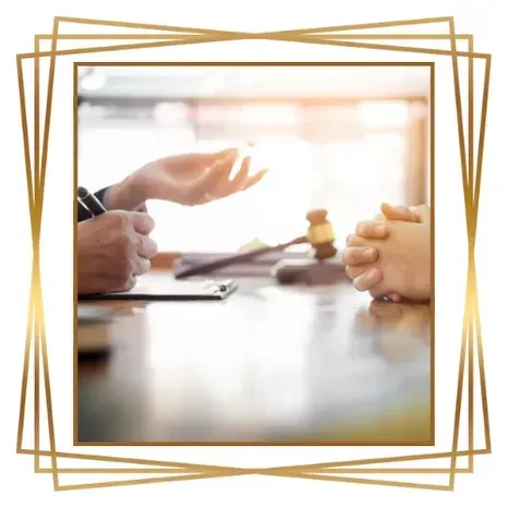 Un abogado discute un documento con un cliente, con un mazo sobre la mesa.