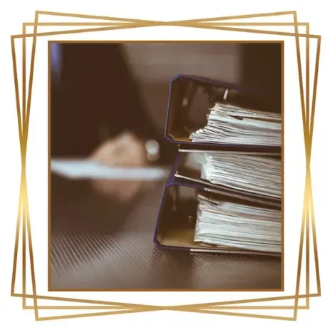 Dos carpetas apiladas sobre un escritorio con una mano borrosa al fondo.