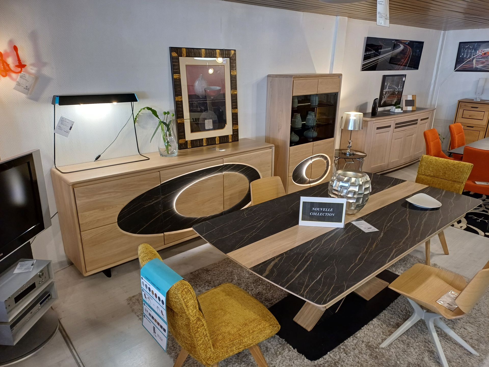 Salle d'exposition de meubles avec table à manger et buffets en bois et accents noirs.