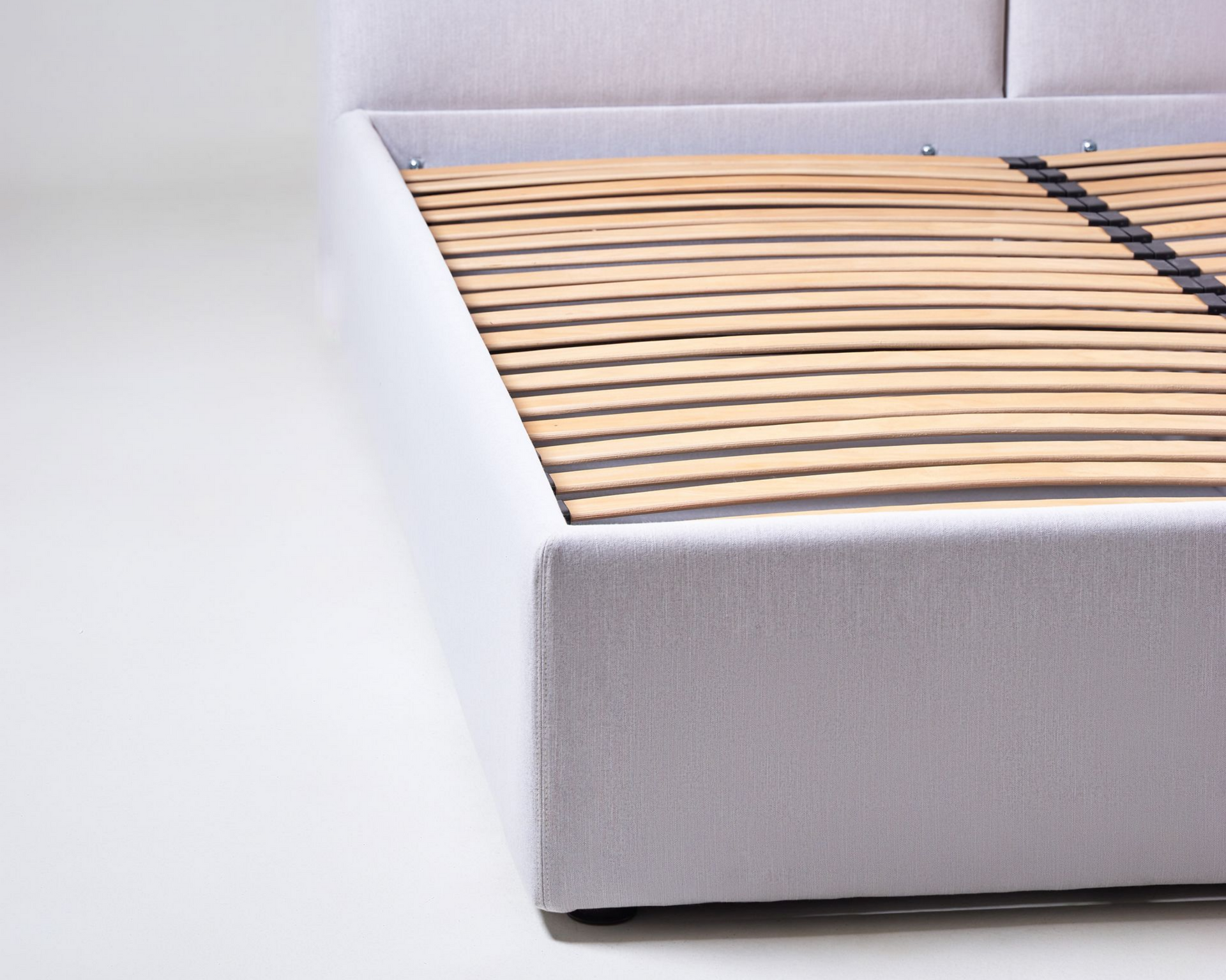 Cadre de lit gris capitonné avec sommier à lattes en bois.