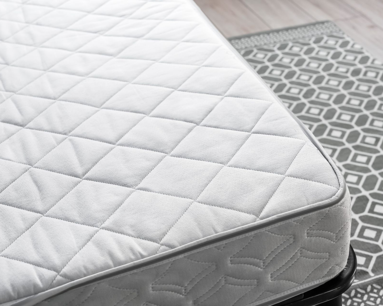 Matelas blanc avec dessus matelassé et bordure grise.