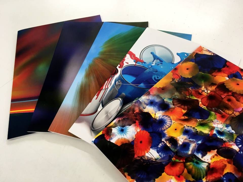 Ein Stapel bunter, bedruckter Broschüren mit abstrakten und fotografischen Abbildungen.