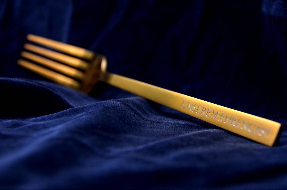 Eine goldene Gabel ruht auf blauem Stoff.