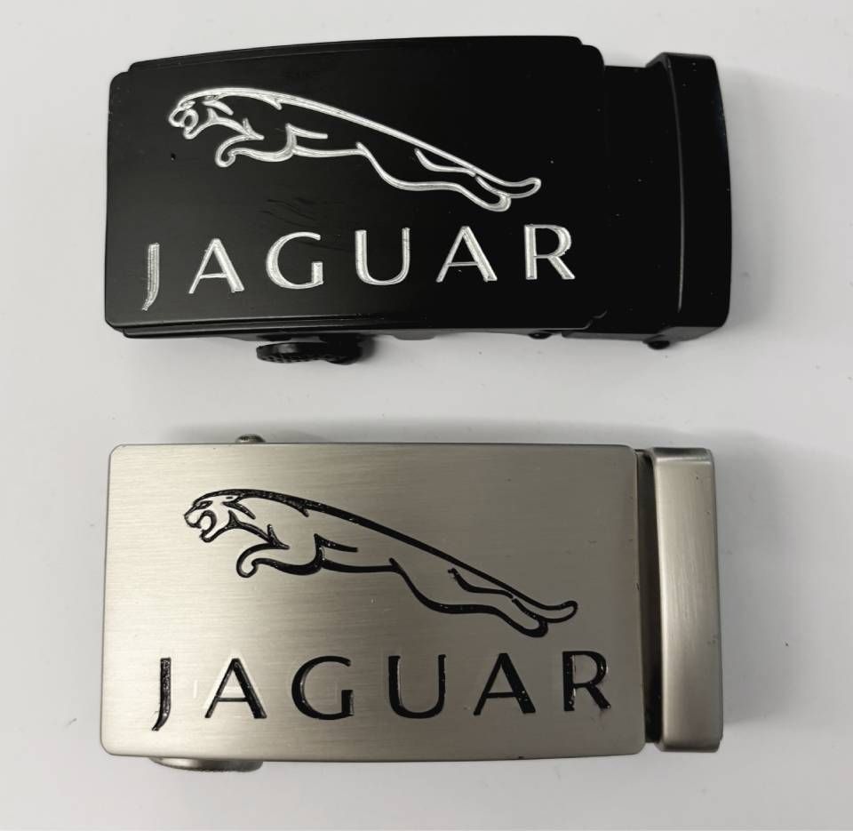 Zwei Jaguar-Gürtelschnallen: schwarz und silber, mit Jaguar-Logo und -Schriftzug.