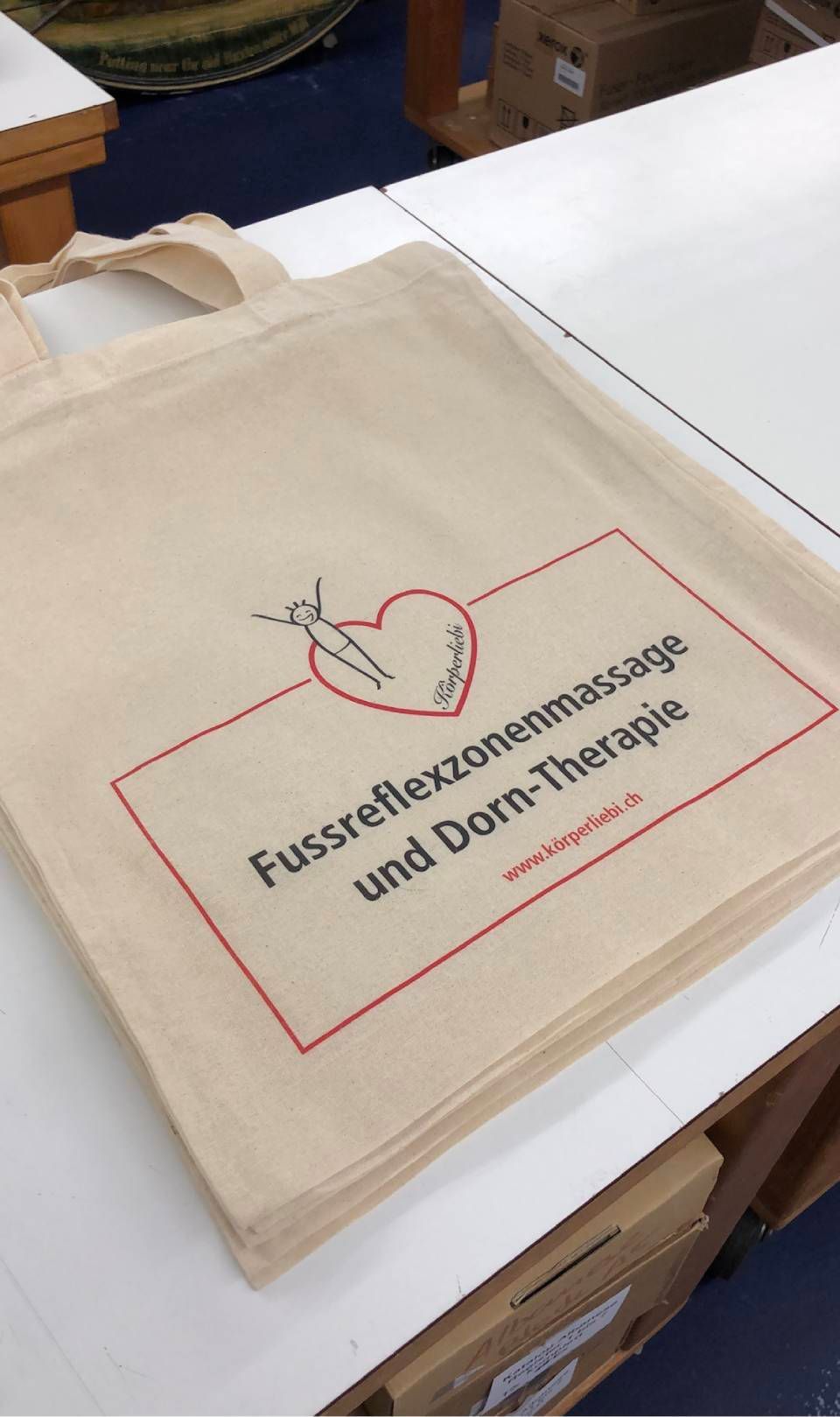 Beige Tragetasche mit rotem Text und Herzsymbol;