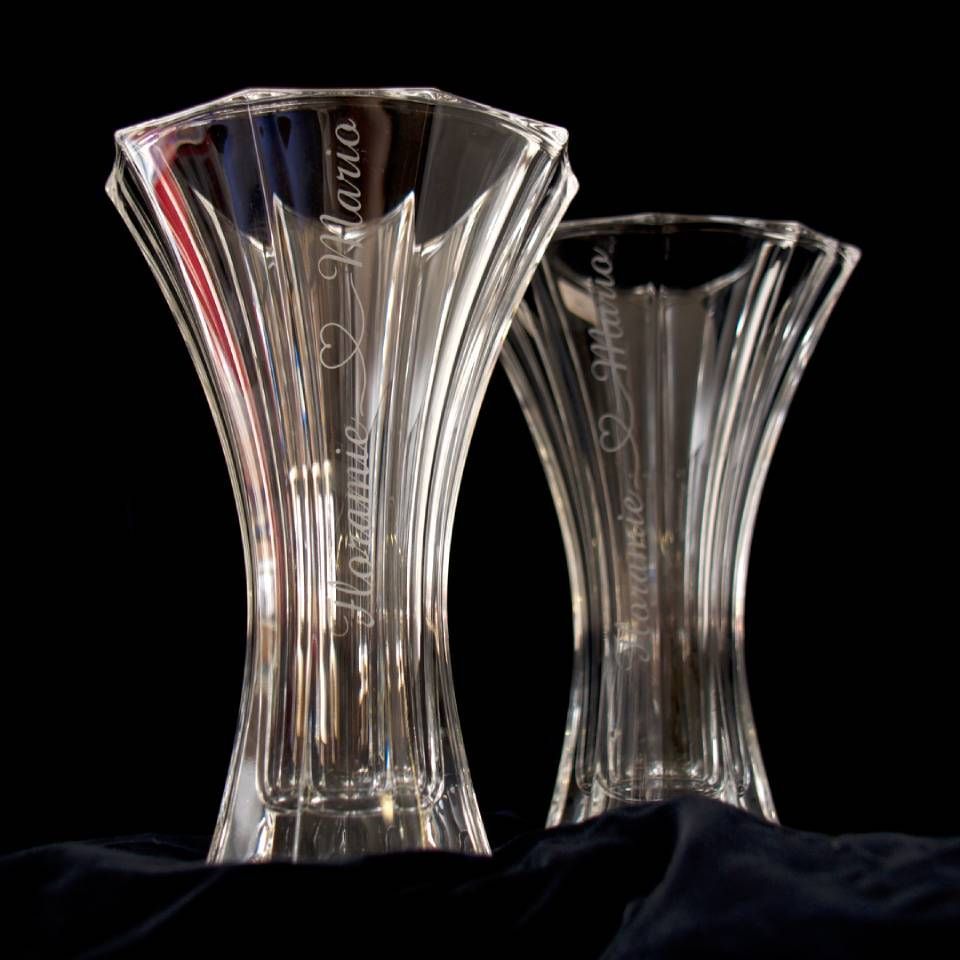 Zwei durchsichtige, gravierte Kristallvasen auf schwarzem Grund. Die Vasen tragen vertikal eingravierte Namen.