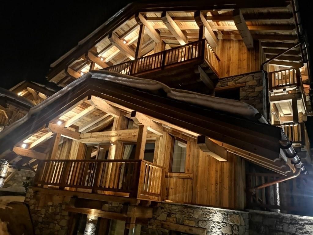 Chalet en bois la nuit, extérieur éclairé de lumières chaudes.