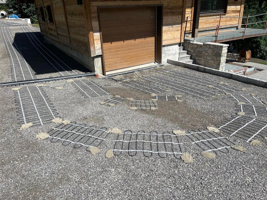 Allée de garage préparée pour le béton, avec un treillis métallique et un réseau de tuyaux.