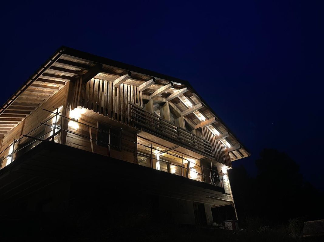 Cabane en bois illuminée la nuit, ciel bleu foncé au-dessus.