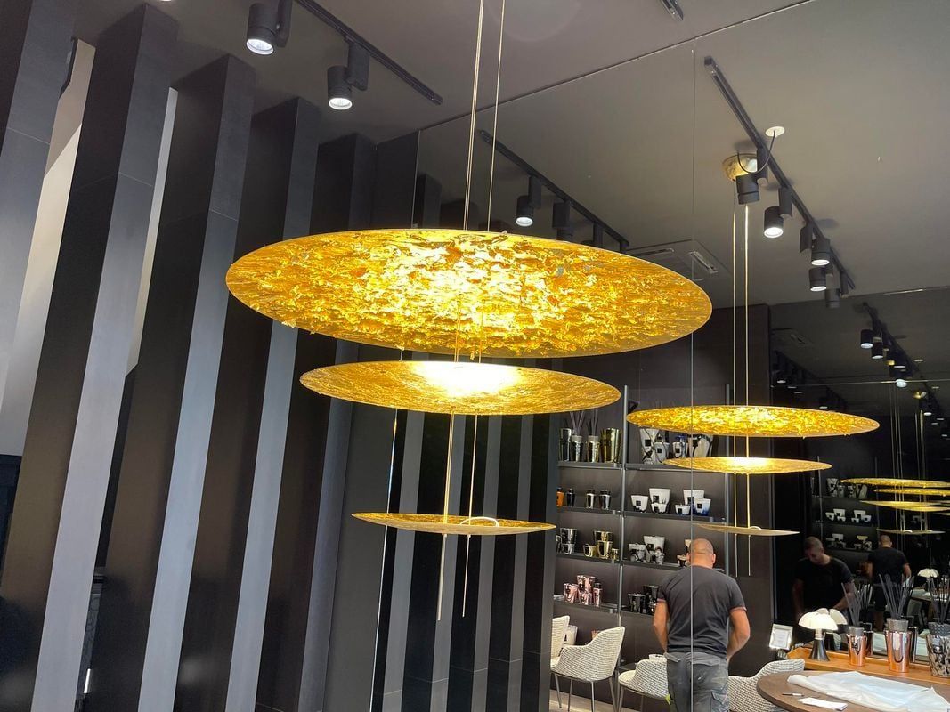 Des suspensions dorées dans la vitrine d'un magasin, une personne regardant à l'intérieur.