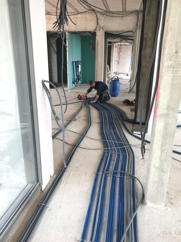 Un ouvrier du bâtiment travaille sur le câblage électrique d'un immeuble en construction.