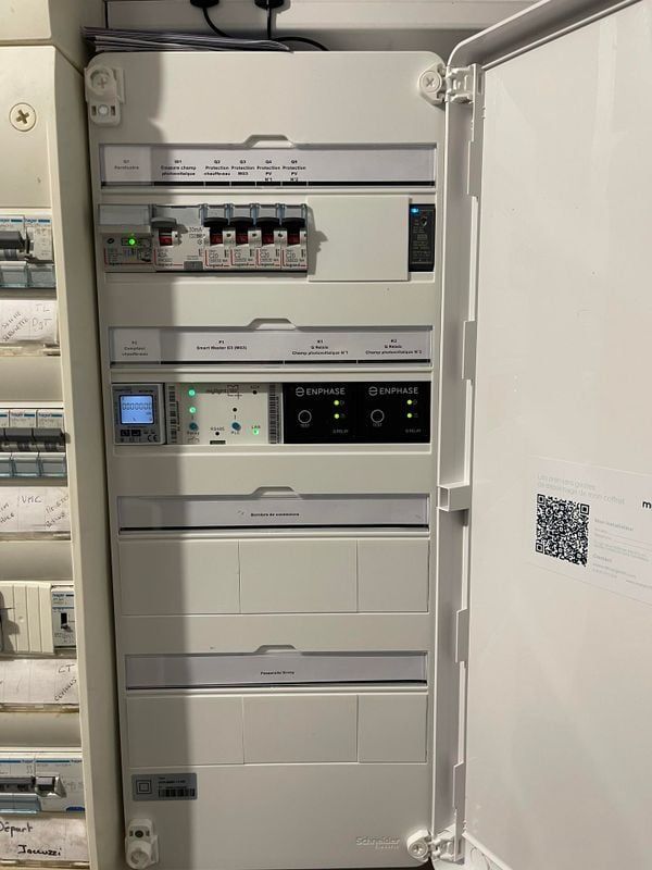 Panneau électrique blanc avec divers composants étiquetés et porte ouverte.