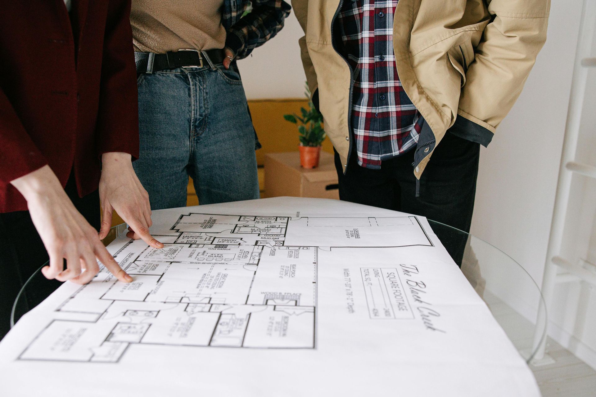 Personas revisando el plano de una casa sobre una mesa en una habitación luminosa.