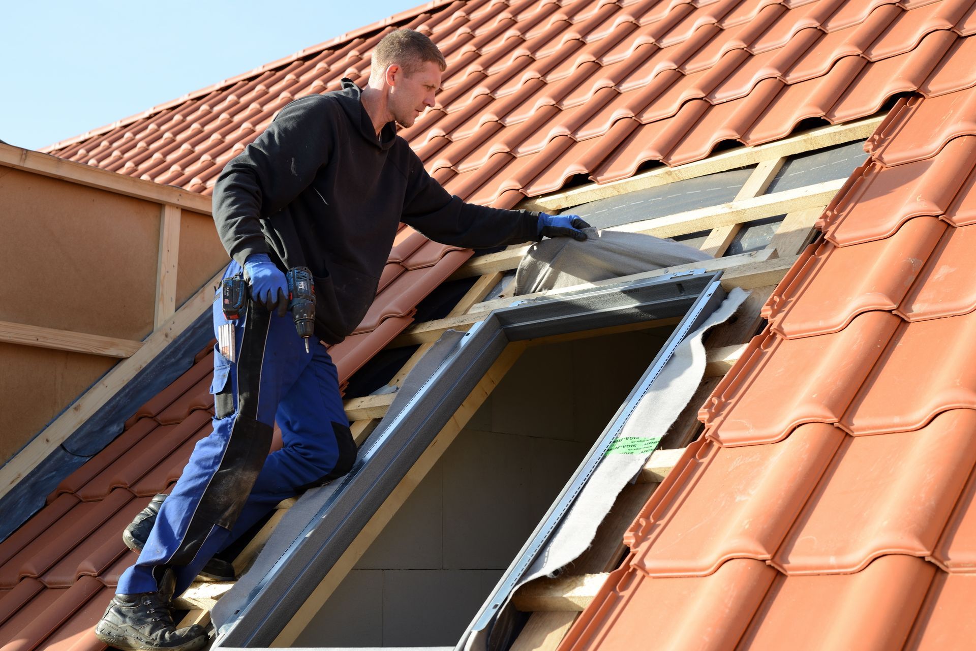 Un homme pose un Velux® sur le toit d'une maison