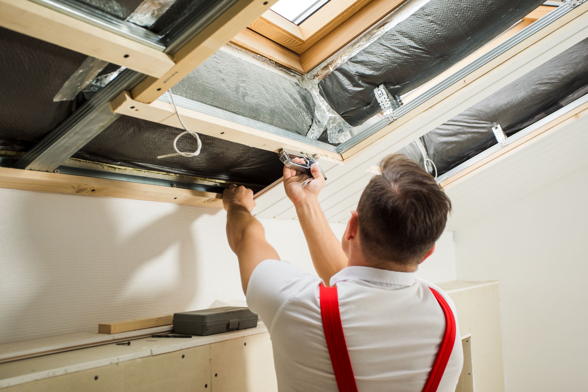 Un homme installe un Velux® depuis l'intérieur d'une maison