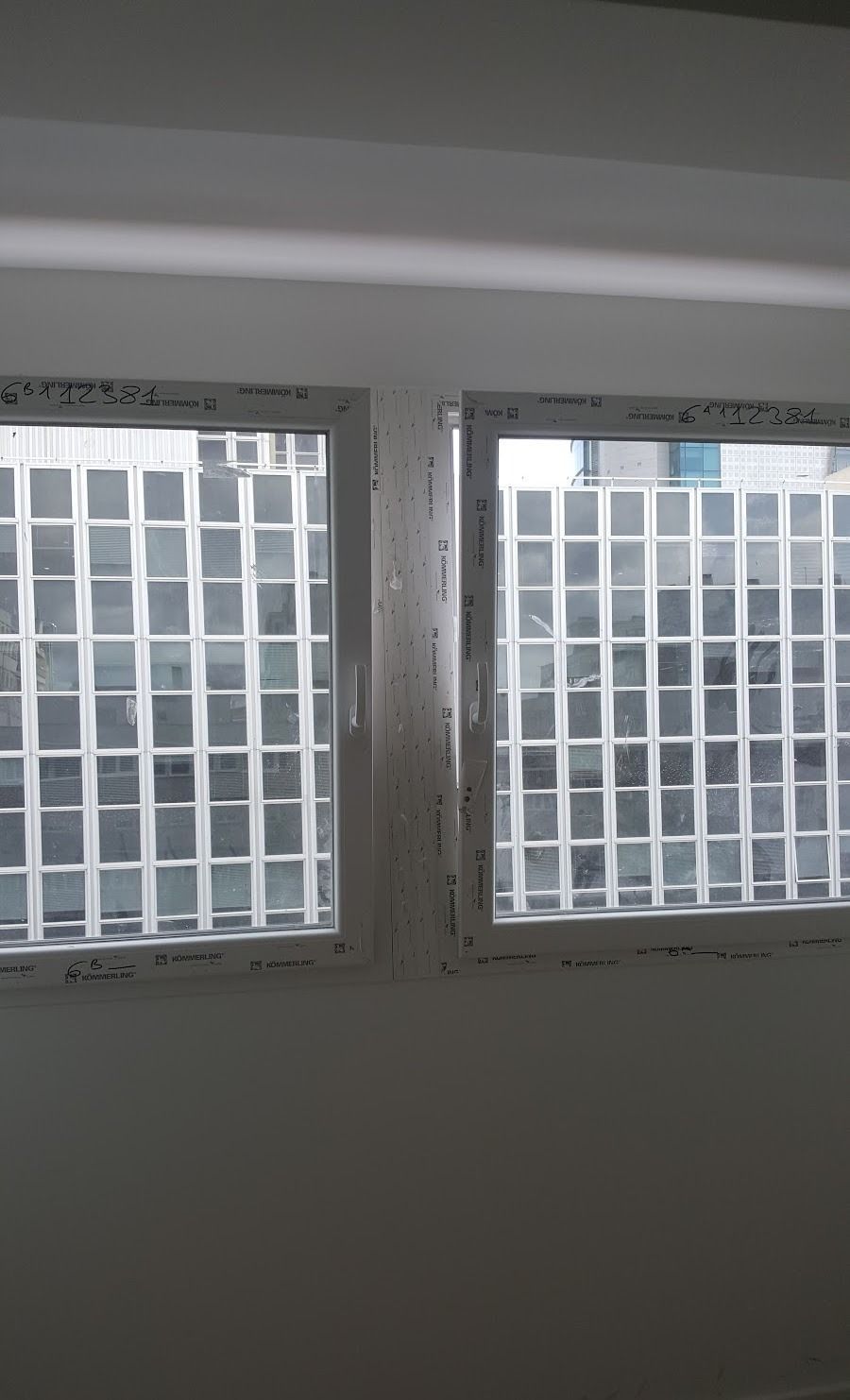Ventana esquinera con persianas blancas y vista al exterior del edificio.