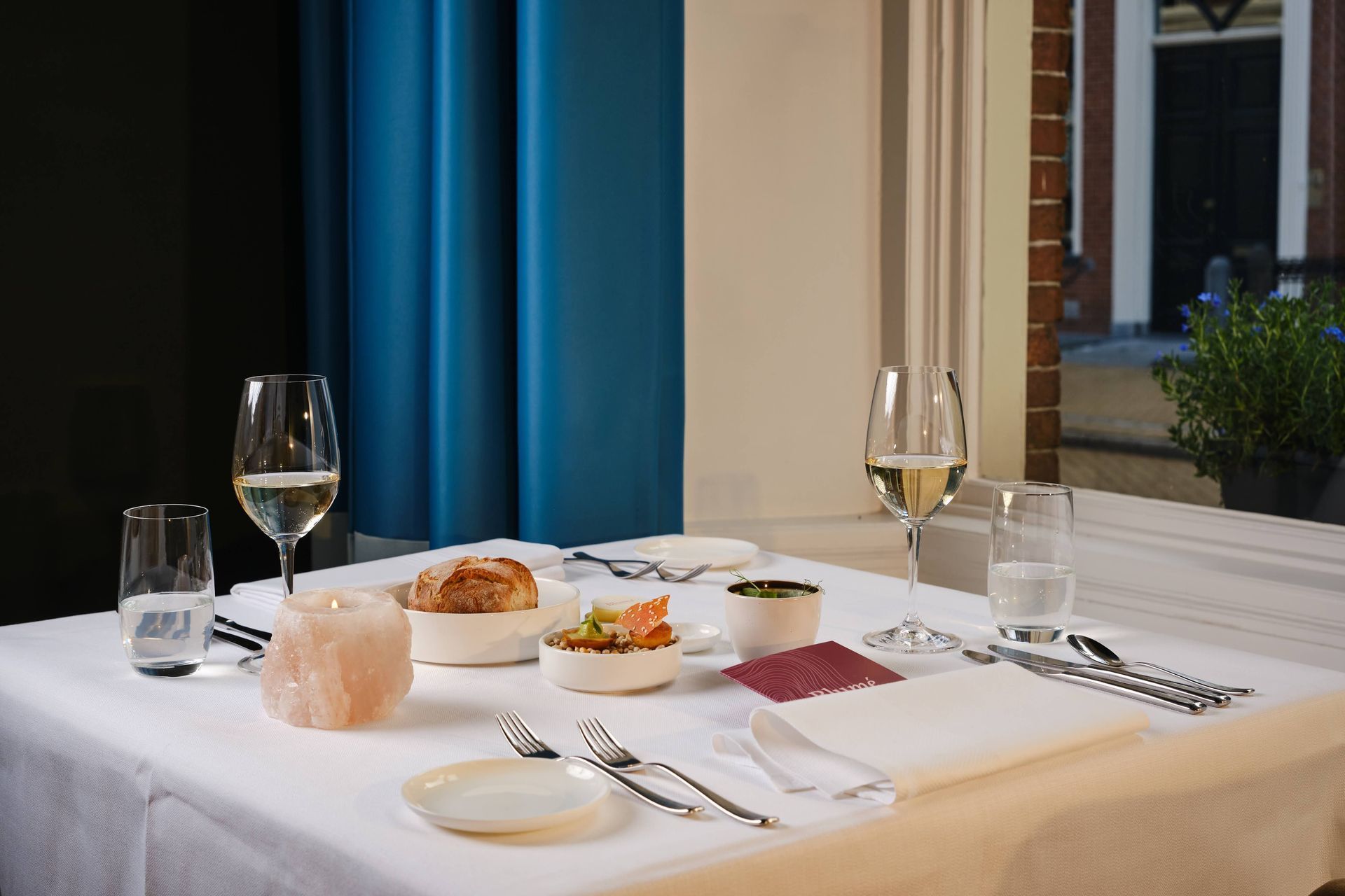 Een tafel met borden, kommen en glazen wijn erop.