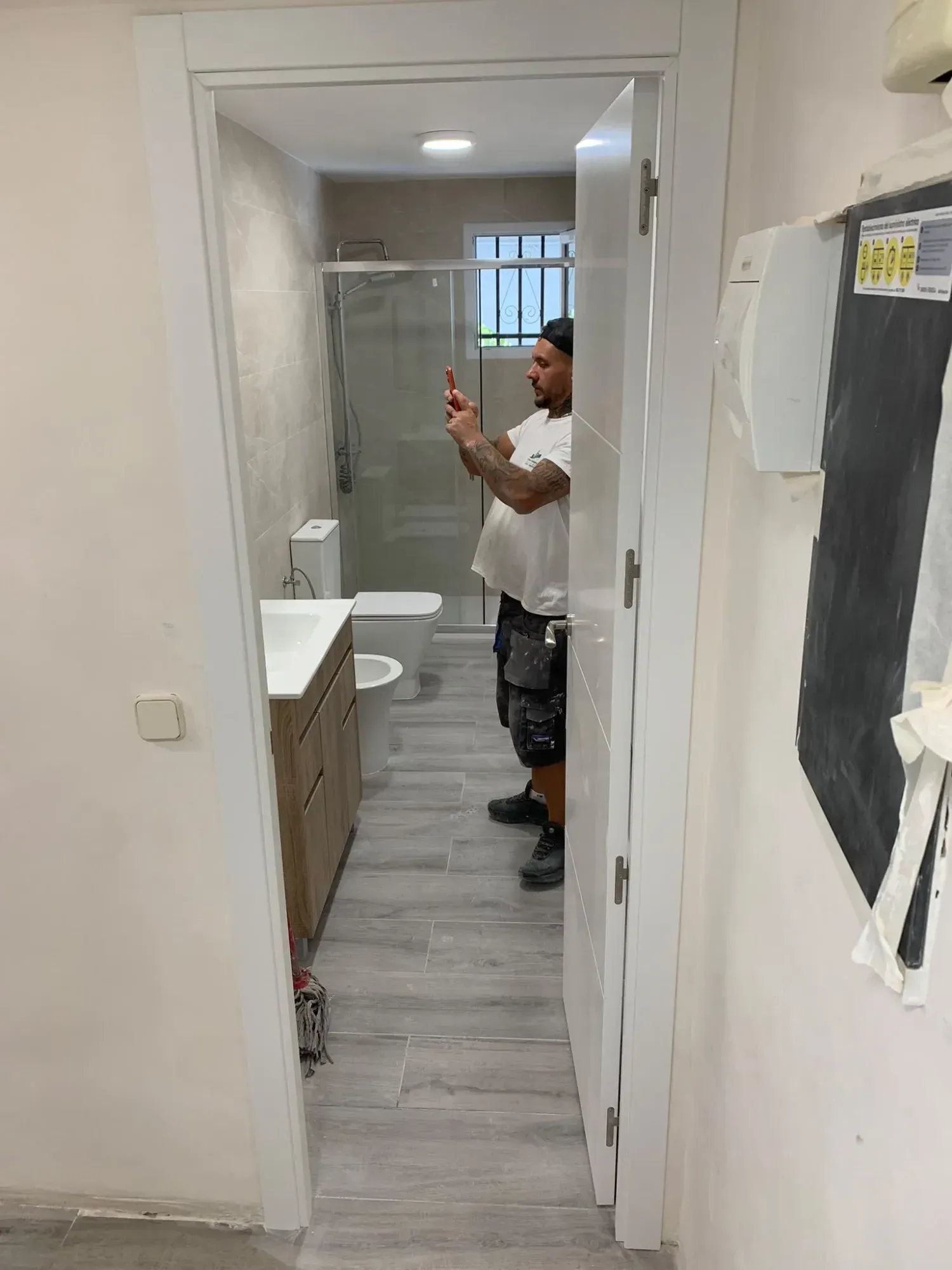 Hombre haciéndose una autofoto frente al espejo en un baño pequeño y blanco en obras