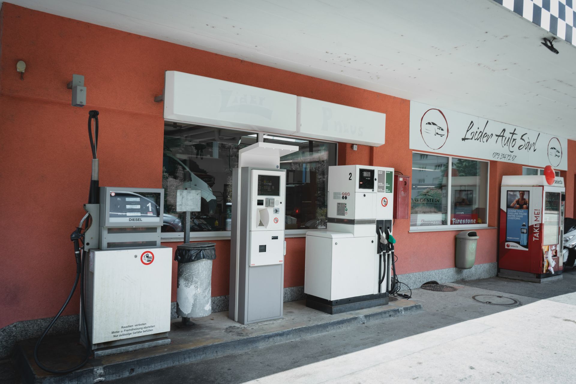 Un mécanicien écrit sur un presse-papiers tout en travaillant sur une voiture.
