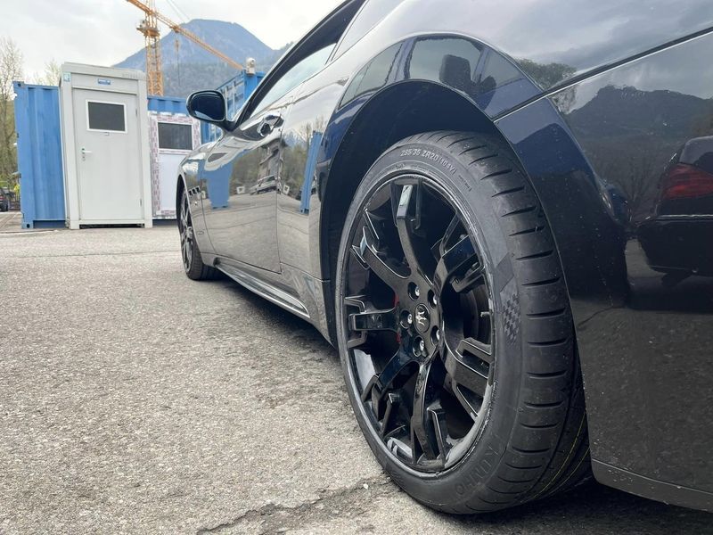 Une voiture de sport noire est garée sur le bord de la route.