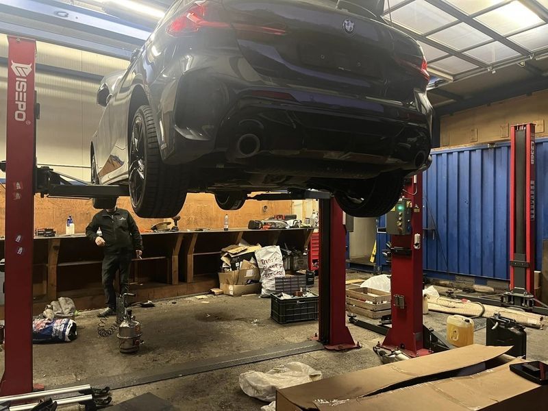 Une voiture est assise sur un ascenseur dans un garage.