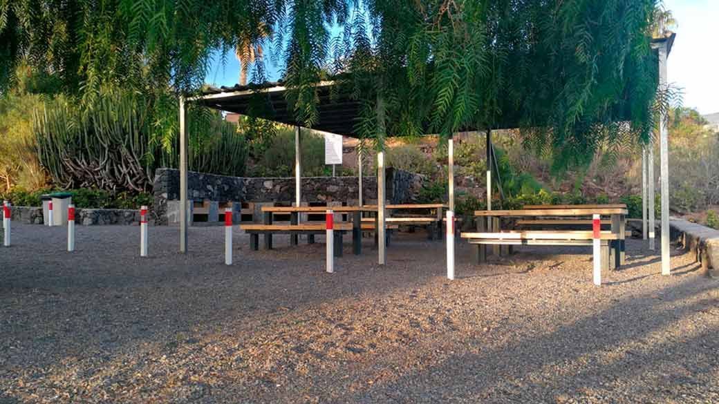 Una zona de picnic con mesas y bancos bajo un dosel.