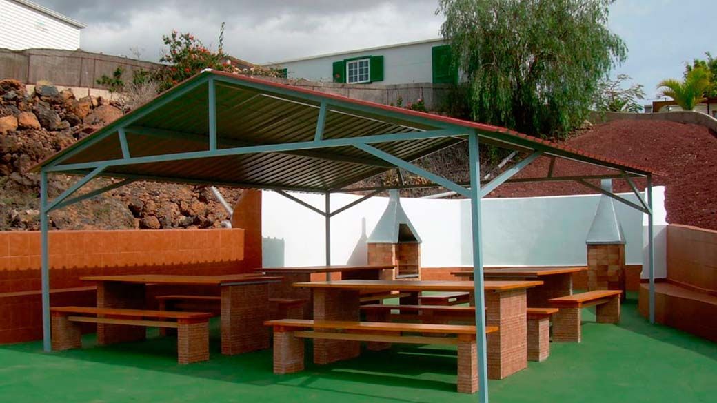 Un área de picnic con mesas y bancos bajo un dosel.