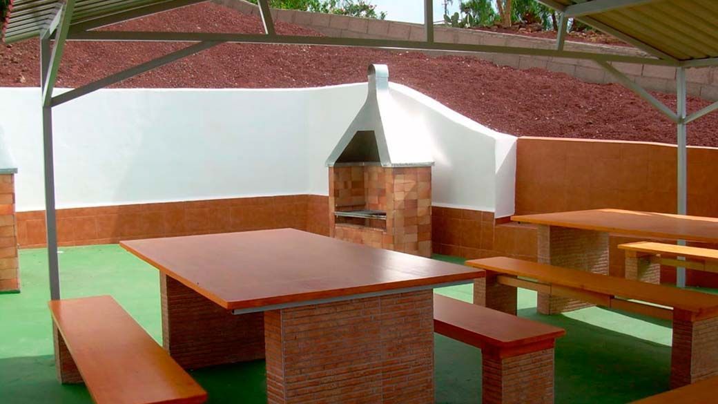 Un patio con una mesa y bancos bajo un dosel.