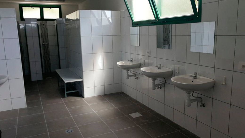 Un baño con muchos lavabos y un banco.