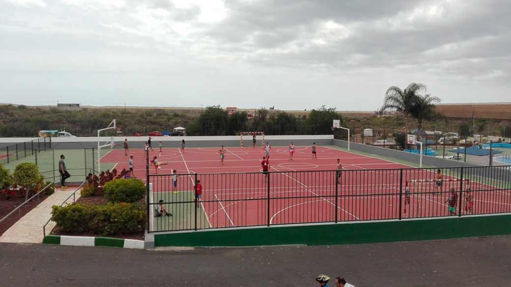 Un grupo de personas está jugando al tenis en una cancha de tenis roja.
