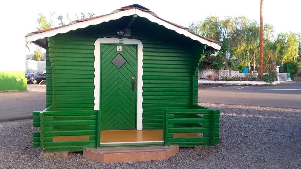 Una pequeña casa verde con un borde blanco y una puerta verde.
