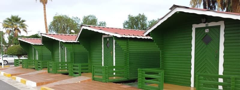 Una hilera de casas verdes con techo rojo están alineadas una al lado de la otra.