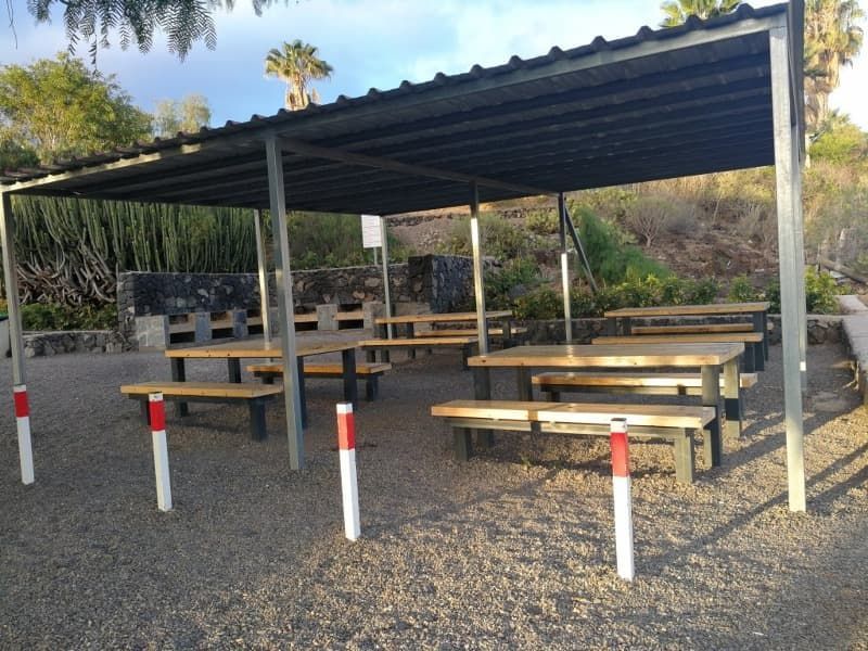 Una fila de mesas de picnic debajo de un área cubierta