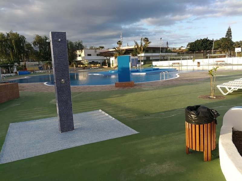 Una piscina con ducha y papelera